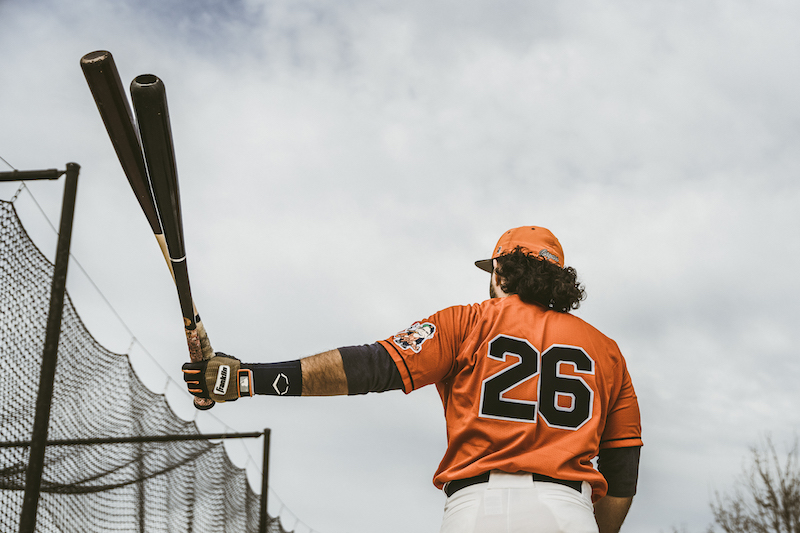 Cigars player #26 preparing for batting practice with multiple bats